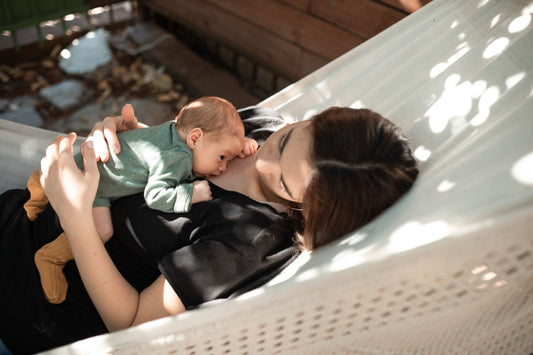 A mother lying in a hammock with her baby